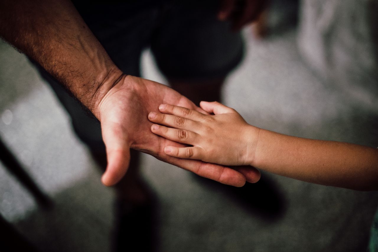 The Art of Drawing Readers In: Your attractive post title goes here Close-up of a child's hand resting gently on a man's hand, symbolizing love and support.