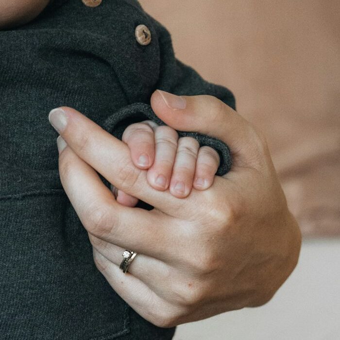 A close-up of a baby gently holding a parent's hand, symbolizing love and care.