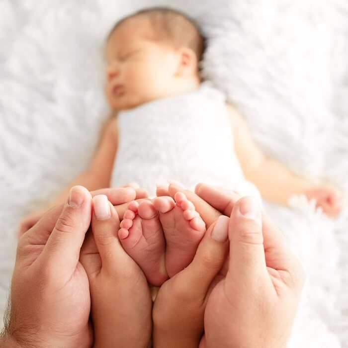 Tender moment of parents holding newborn's feet, symbolizing love and care.